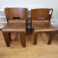 Front view of four stacked molded wood chairs showing wear on finish.