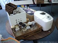 Bread maker alongside assorted canning jars and other household items on a round table.