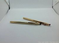 Two gold fill CROSS pens placed side by side, showcasing their polished gold-tone finish and clips.