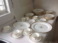 Overview of full set on countertop showing plates, cups, saucers, and serving pieces