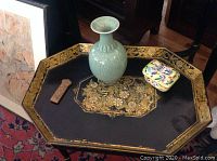 Photo showing all three Asian decorative objects on an octagonal tray: celadon vase, hardstone carved pendant, and famille jaune lidded container.