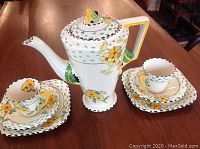 Overview of coffee pot and two complete trios on wooden table