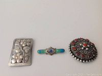 All three brooches displayed side by side on neutral background