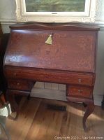 Closed view of desk showing drop front, cabriole legs and inlaid marquetry