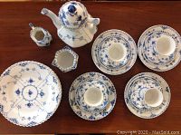 Overhead view of entire set arranged on wooden table showing plates, cups, saucers, teapot, creamer and sugar bowl