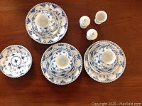 Overhead view of three demitasse cup, saucer and luncheon plate sets alongside lone luncheon plate, egg cup, salt and pepper shakers