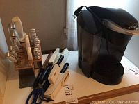 Overall view of Keurig coffee maker next to kitchen knife sets including KitchenAid knives in wooden block and loose knives with scissors