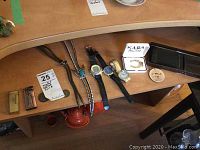 Full view of men's watches, bolo ties, lighters, wallet and other accessories spread on a wooden surface.