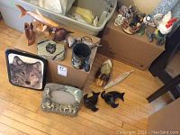 Photo of assorted decor items including animal figurines on boxes and floor.