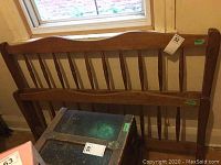 Wooden double size headboard and footboard leaning against wall by window