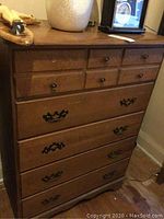 Full view of vintage wooden dresser with five drawers and mixed metal handles.