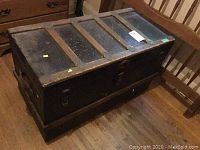 Top view of the vintage metal and wood trunk showing the wooden slats and metal panels with rust spots and worn paint.