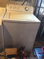 Side view of white top load GE washer showing general condition and placement.