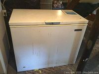 Full view of a white chest freezer showing wear and stains on exterior surfaces.