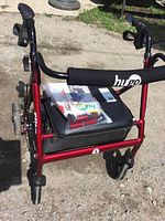 Front view of red Hugo Elite rolling walker showing padded seat, storage area, and manual on top.