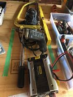Photo showing the Black and Decker Holgun electric drill, yellow frame hand saw, and part of the Stanley power inverter.