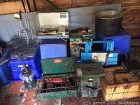 Wide view showing camping stoves, coolers, cooking pot, BBQ grills and utensils, and lantern on floor