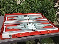 Top view of the folding table and seats in collapsed state showing metal frame and locking clamps.