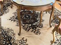 Large area rug under table showing floral design in dark brown and cream colors
