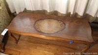 Coffee table showing medium brown wood surface with large circular water or heat stain in the center and additional smaller stains near the edges.