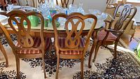 Back view showing the carved double loop wooden design on backrests of dining chairs around a table.