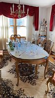 Full view of wood dining table with one leaf inserted, covered with glassware (not included). Shows curved legs and wood finish.