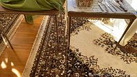 Close-up photo showing the side legs of two card tables with a patterned carpet underneath