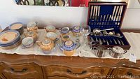 Overview photo of Japanese Lusterware tea set with coffee pots, sugar bowl, creamer, cups, saucers, bread plates all arranged on a sideboard with the flatware case visible to the right.