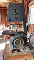 Front view of Delta Rockwell band saw showing exposed pulley and cutting table with wood base.