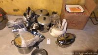 Overall lot featuring pots, bowls, food processors, and glassware arranged on floor with cardboard box