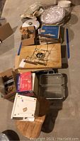 Overview of lot from above showing all items including boxed Rival Salad Maker attachment, boxed crystal pitcher, wooden cutting boards, glassware, scale and cookware.