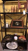 Shelf display showing multiple clocks, decorative items, martini glasses, and carved wooden stands.