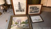 Four framed wall art pieces arranged on floor with lamp and cabinet in background showing overall condition and framing