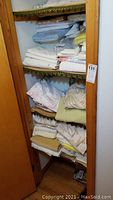 Shelves of folded bed linens and blankets in various colors and patterns