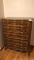 Front view of the five drawer wooden dresser showing decorative carved drawer fronts and metal handles