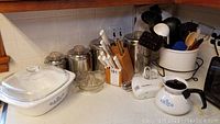 Photo showing Corningware Blue Cornflower bakeware, metal canisters, knife block, handheld mixer, and some kitchen utensils.