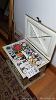 Open sewing chest showing assorted thread spools, pincushion, scissors, and sewing notions