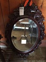 Full front view of the oval mirror showing carved wooden frame and beveled glass.
