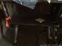 Close-up photo showing the turned legs and bottom shelf of the wooden library table.