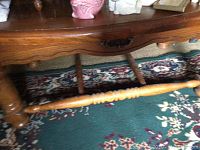 Close-up of the furniture legs and stretcher bar of a wooden table showing turned details and wood grain.