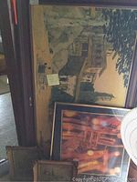 Large framed painting featuring stone building with greenery and old architecture