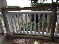 Wooden signs displayed hanging on a white wooden railing, including one sign with 'JESUS' painted on it.