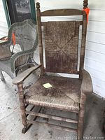 Front view of wooden rocking chair with rush seat and backrest on porch