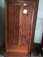 Full front view of dark wood chifferobe cabinet with two doors, wooden knob, and natural wood grain.