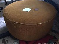 First brown round ottoman showing overall shape and fabric condition with visible wear.