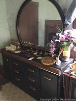 Photo of the dresser with decorative items on top and the large oval mirror behind it.