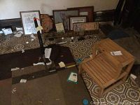 Wooden step stool, metal exercise bar, and assortment of framed art pieces set on a patterned floor inside a room.