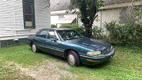 Passenger side view of green Buick LeSabre parked on grass