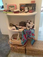 Overview of cat-themed items displayed on shelves, some books, figurines, baskets, silk scarf, and umbrella visible.