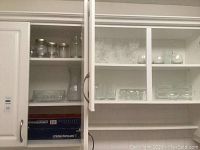 Glass cabinet with multiple rows of glassware including clear jars, Crystal D'Arques wine glasses, and bowls.